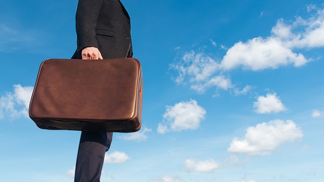 salesperson holding suitcase against blue sky
